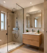Salle de bain avec douche vitrée et meuble en bois.